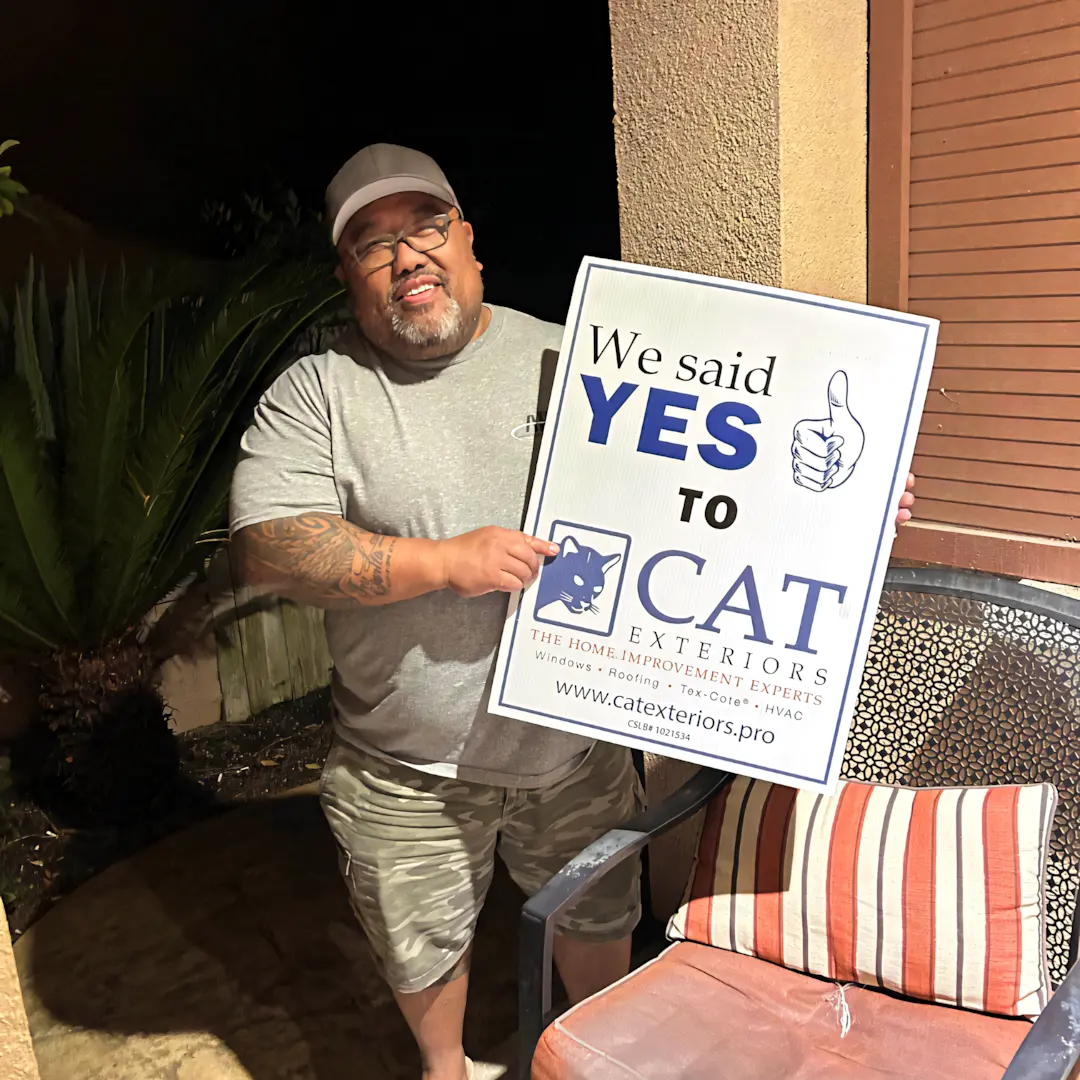 A full color 1080x1080 webp image of a happy CAT Exteriors client in front of their home.