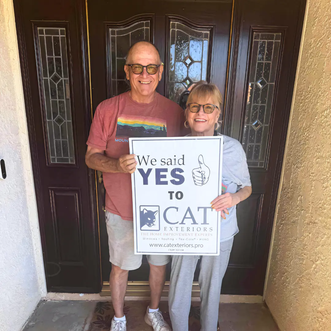 A full color 1080x1080 webp image of a happy CAT Exteriors client in front of their home.