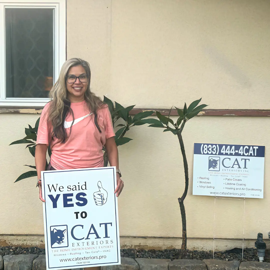 A full color 1080x1080 webp image of a happy CAT Exteriors client in front of their home.