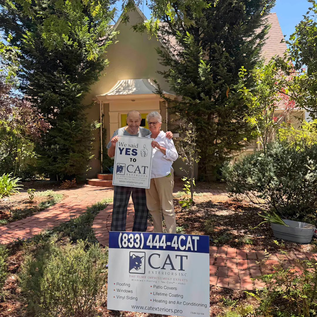 A full color 1080x1080 webp image of a happy CAT Exteriors client in front of their home.