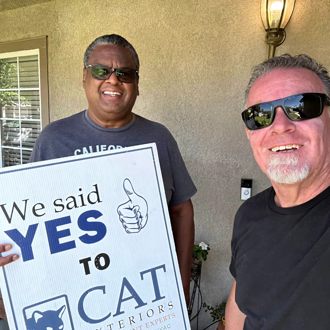 A full color 1080x1080 webp image of a CAT Exteriors representative taking a photo with a happy client at their home.