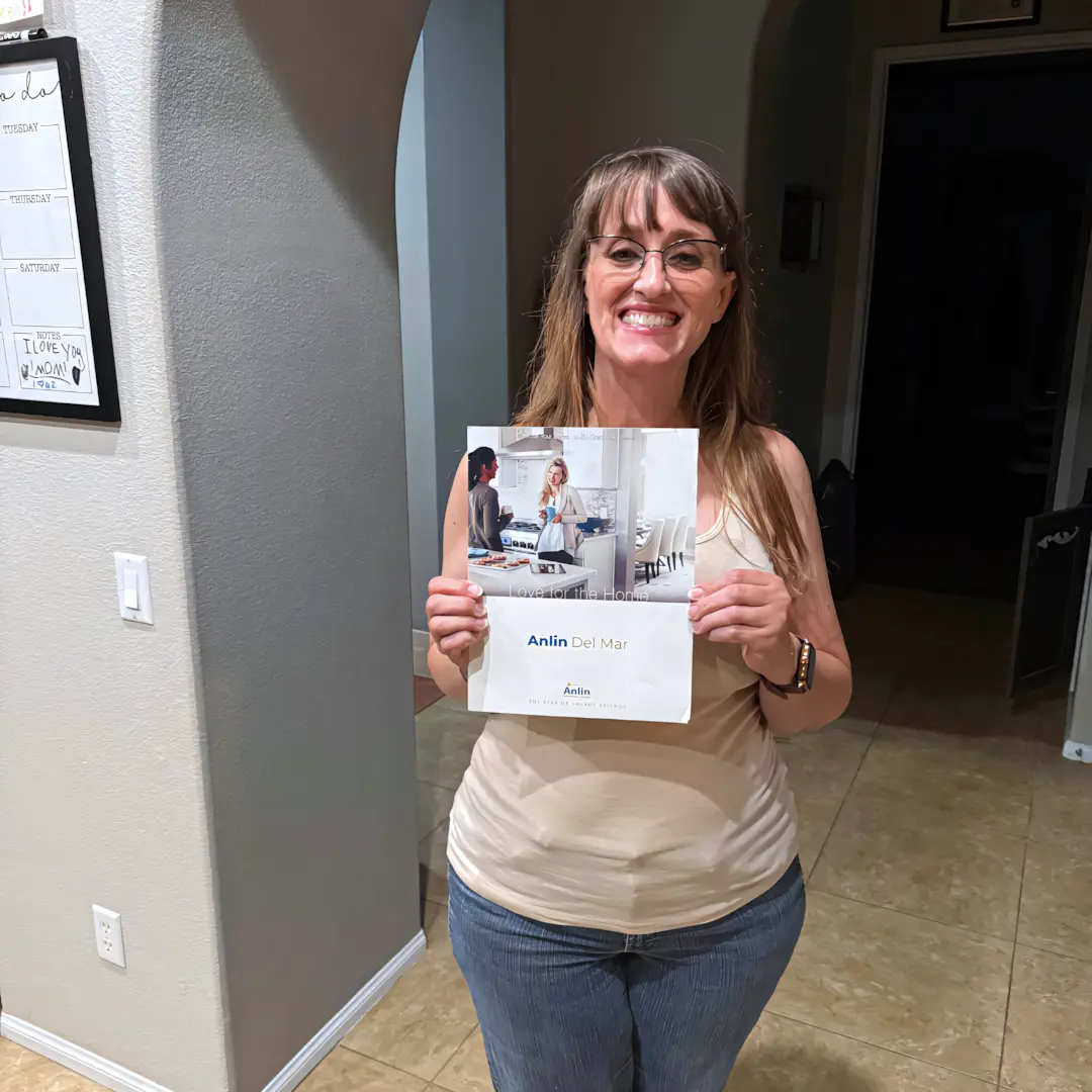 A full color 1080x1080 webp image of a happy CAT Exteriors client in front of their home.