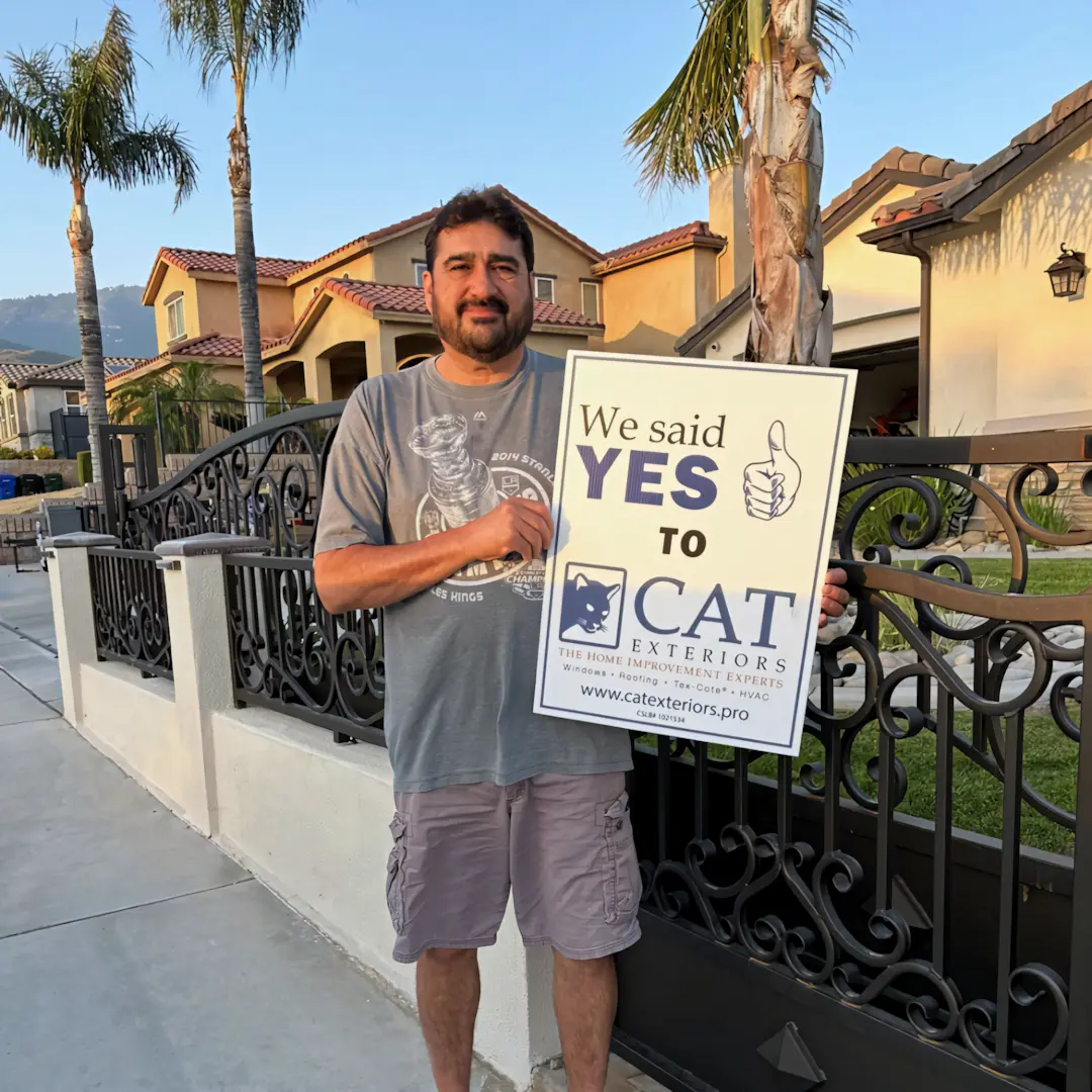 A full color 1080x1080 webp image of a happy CAT Exteriors client in front of their home.