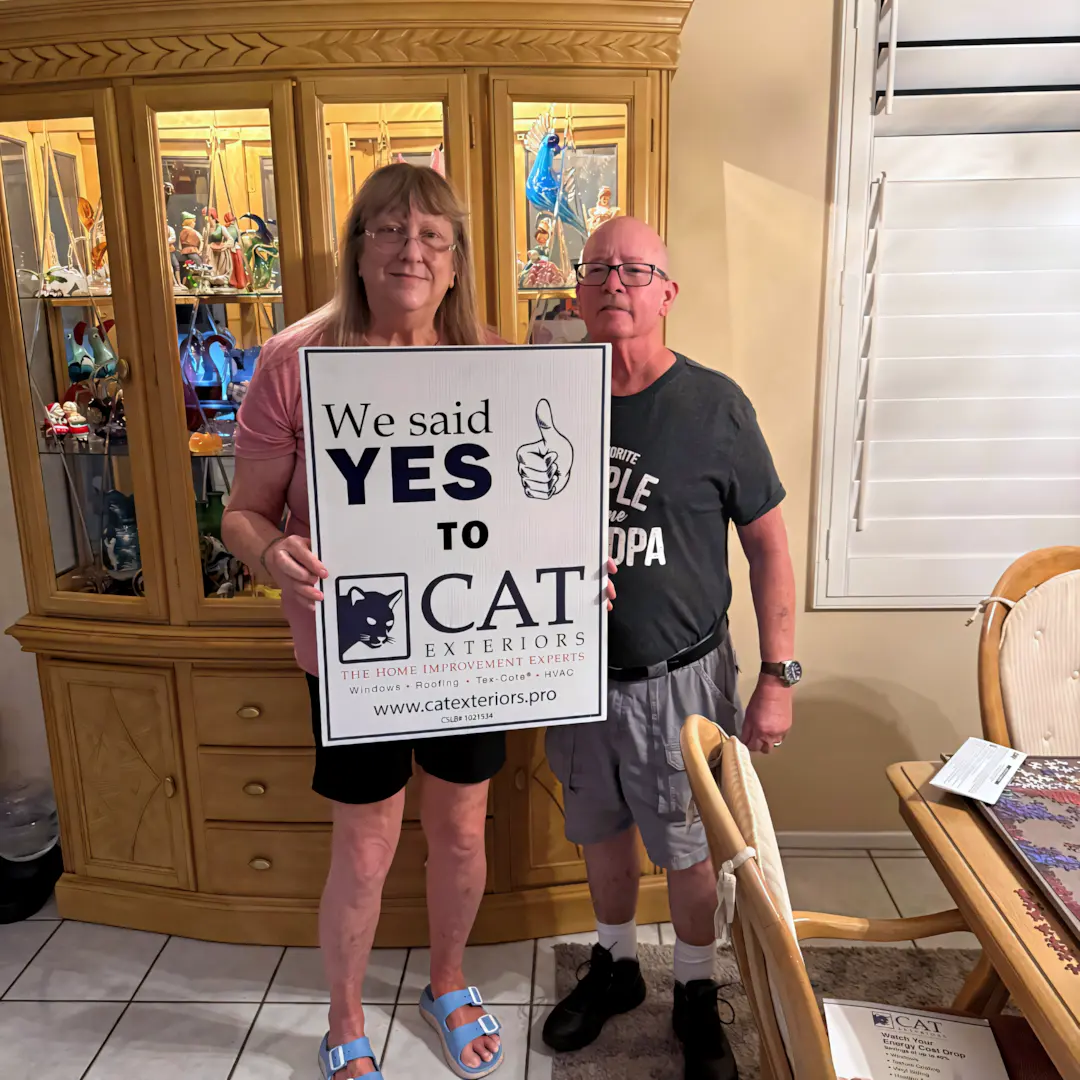 A full color 1080x1080 webp image of a happy CAT Exteriors client in front of their home.