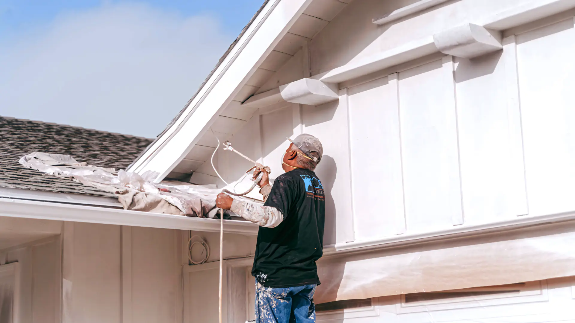 A full color 1920x1080 webp image of a CAT Exteriors contractor applying our Tex–Cote exterior coating to a home's exterior.