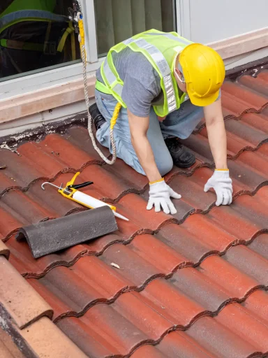 A full color 1080x1440 webp image of a roofer inspecting a tile roof installed by CAT Exteriors.